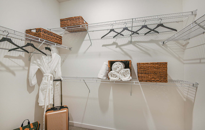 a walk in closet with a white robe and wicker baskets