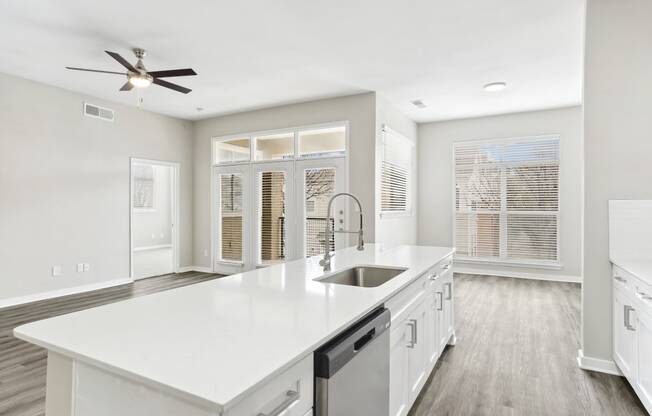 a large white kitchen with a large island and a ceiling fan