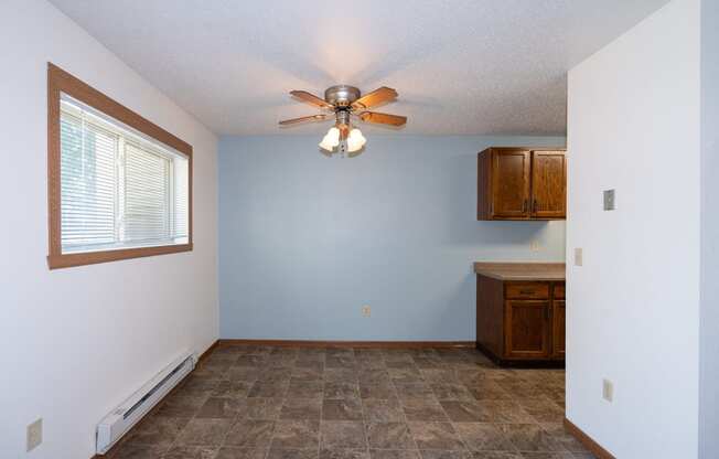 an empty living room with a ceiling fan and a window. Fargo, ND Pacific South Apartments