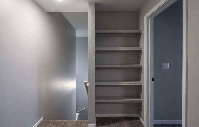 a walk in closet with empty shelves and a door