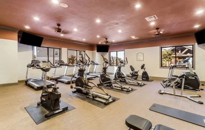 a gym with various pieces of exercise equipment and windows