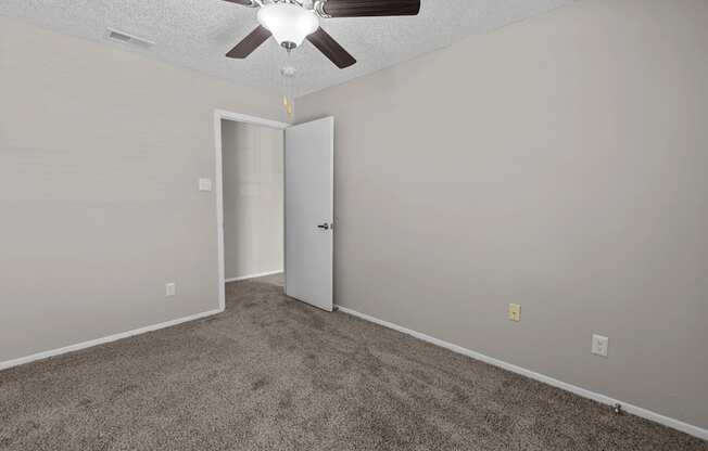 A room with a ceiling fan and carpeted floor.