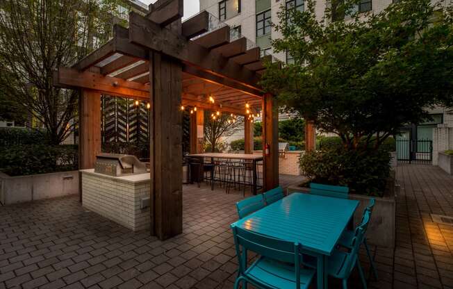 a wooden pergola with a turquoise table and chairs on a brick patio at The Parker, Oregon