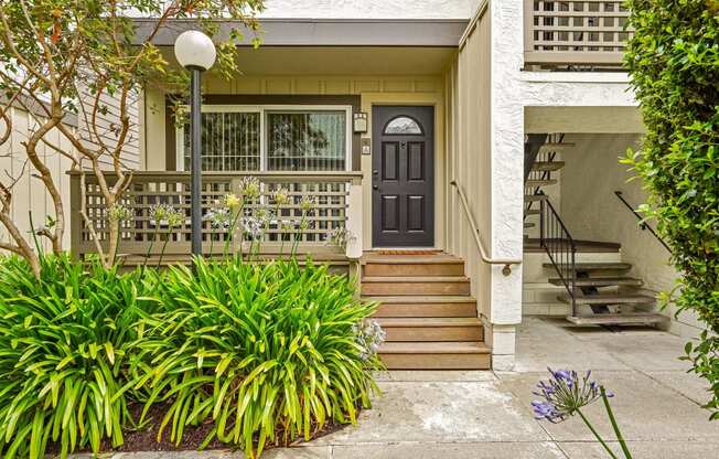 the front of a house with stairs and a black door