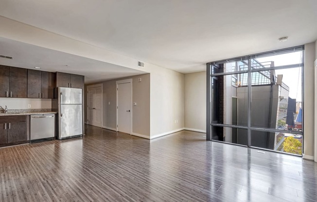 an empty living room with a kitchen and a glass door