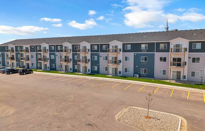 A parking lot in front of a large apartment complex.
