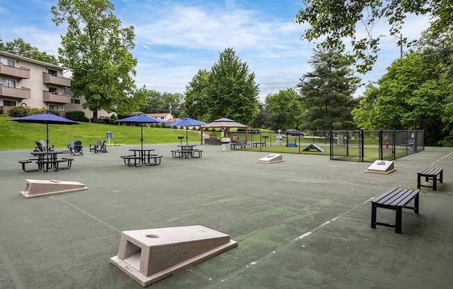 A park with a basketball court, picnic tables, and umbrellas.