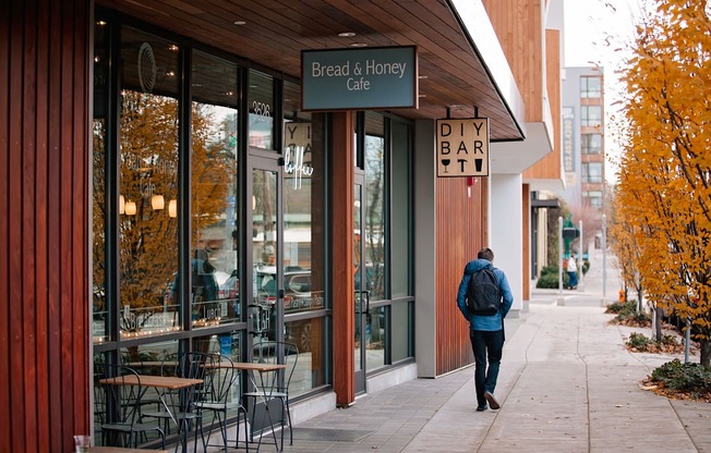 a man walking down a sidewalk in front of a bar