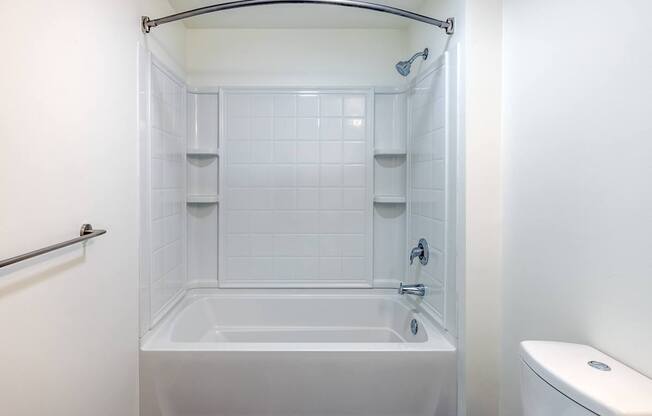 A white bathroom with a tub, toilet, and shower.