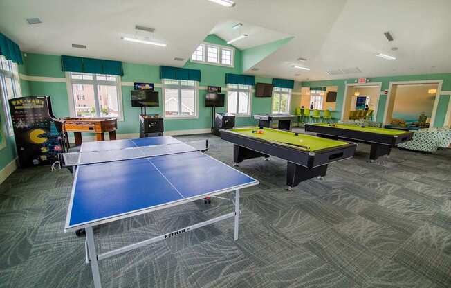 A room with a ping pong table and a foosball table.