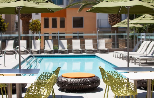 a pool with green chairs and umbrellas