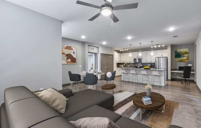 a living room and kitchen with a couch and a ceiling fan
