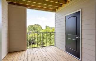 A balcony with a black door and a view of trees at Mode at Melbourne, LLC Apartments, Florida, 32901