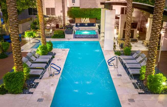 A swimming pool surrounded by palm trees and lounge chairs.