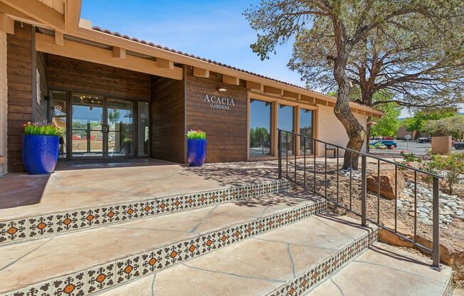 a building with stairs and a glass door with a tree in front of it at Acacia Gardens, Albuquerque, NM, 87111