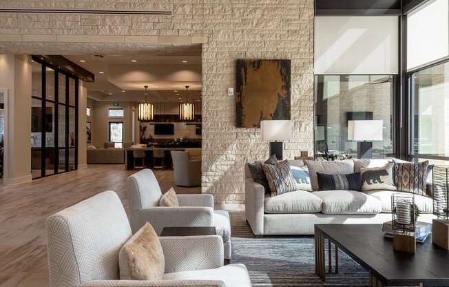 A living room with a white brick wall and a large abstract painting above a sofa.