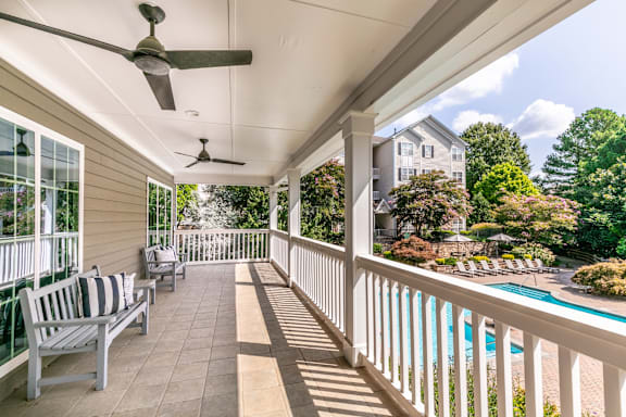 the back porch of a house with a pool and a porch swing