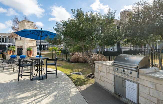 a patio with a grill and a table with chairs and an umbrella  at Orion Prosper Lakes, Prosper
