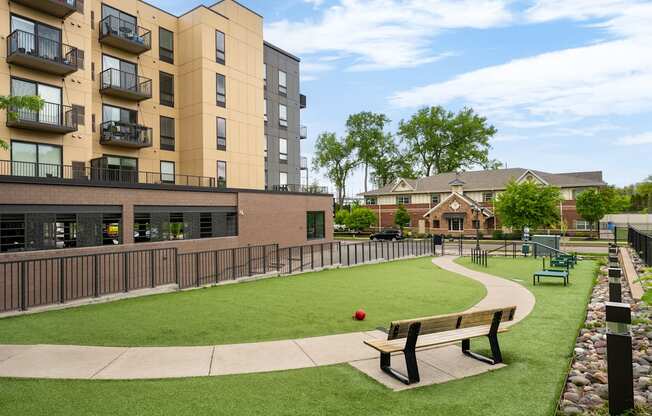an apartment community with a park with benches and a ball on the grass