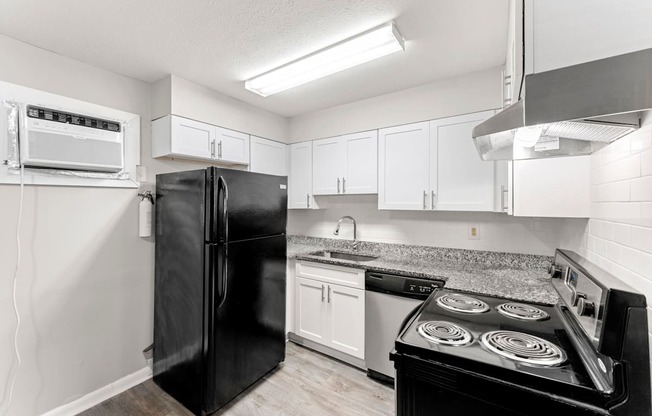 a kitchen with white cabinets and black appliances  at Balfour 296, Georgia, 30047