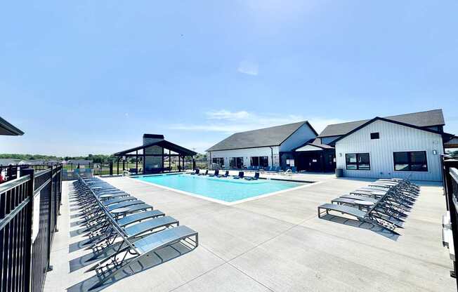 A sunny day at the pool with lounge chairs and a clear blue sky.