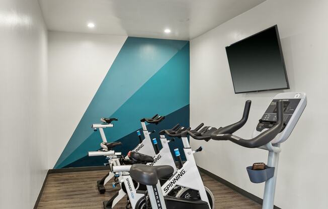 a gym with treadmills and a tv on the wall