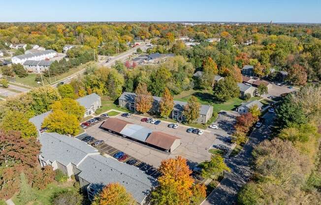 An aerial view of a parking lot surrounded by trees with autumn foliage.