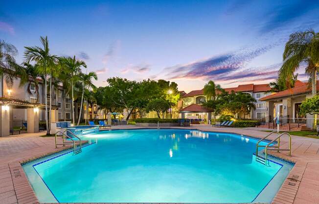 A large swimming pool surrounded by palm trees and a building in the background.