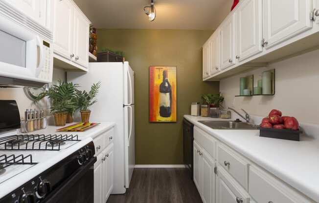 a kitchen with white cabinets and a stove and a refrigerator at Village Club of Rochester Hills, Shelby Township, MI