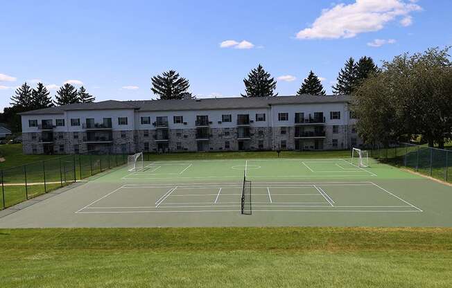 A tennis court is located in front of a large building.