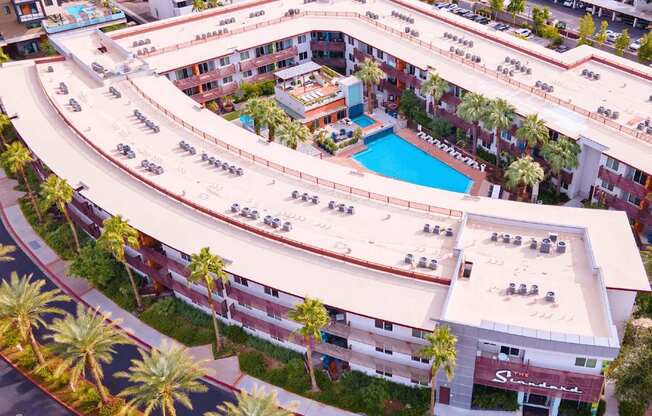 A large apartment complex with a pool and palm trees.