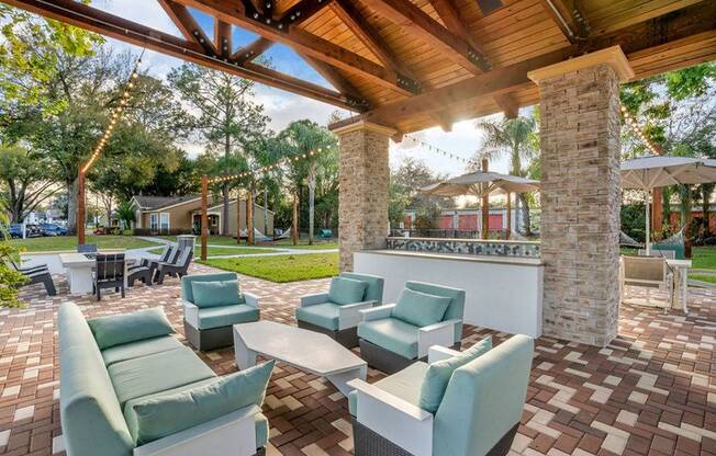 Shaded outdoor seating space with four chairs and a couch. Fire pit amenity in the background.