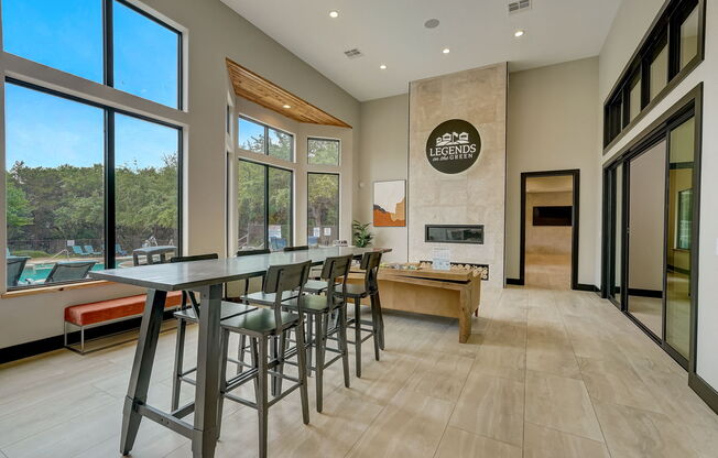 a long bar with stools in a kitchen with large windows