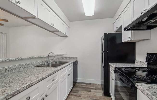 A kitchen with a black refrigerator and white cabinets.
