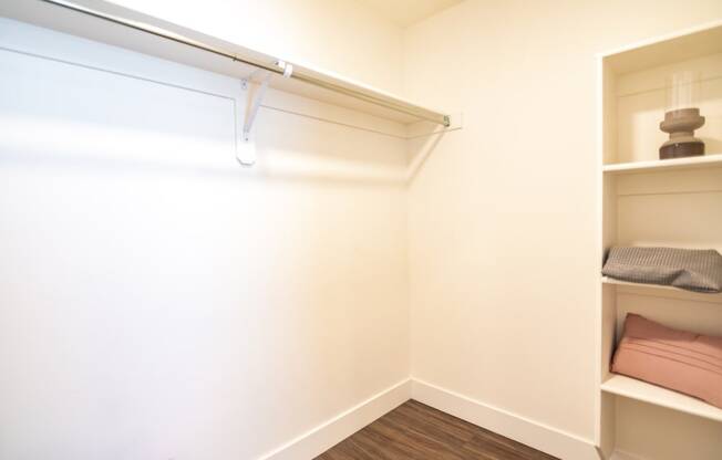 a walk in closet in a small room with shelves and a white wall