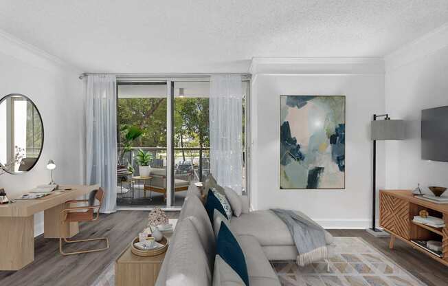 A modern living room with a grey couch and a painting on the wall.