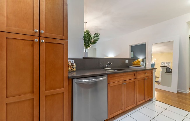 a kitchen with a stainless steel dishwasher and wooden cabinets at Pier Village Apartments, Long Branch, New Jersey