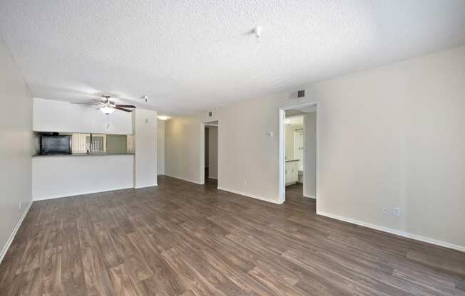 a 2-bedroom apartment living room and kitchen with wood flooring and a ceiling fan