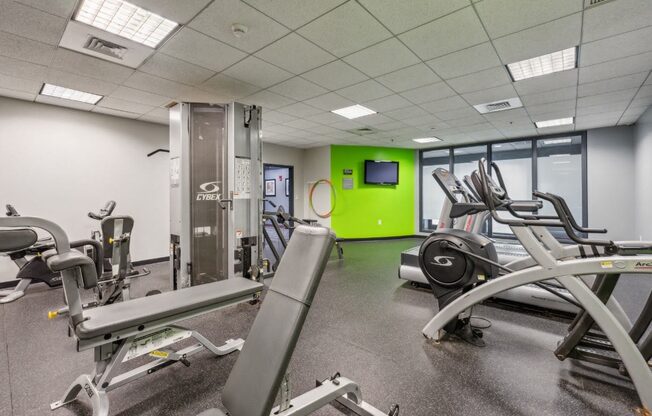 a gym with exercise equipment and a green wall