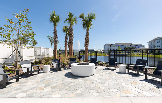 firepit with lounge chairs surrounded by trees and the pond at Lake Nona Concorde