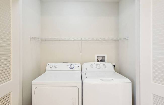 Two white front loading washing machines in a laundry room.