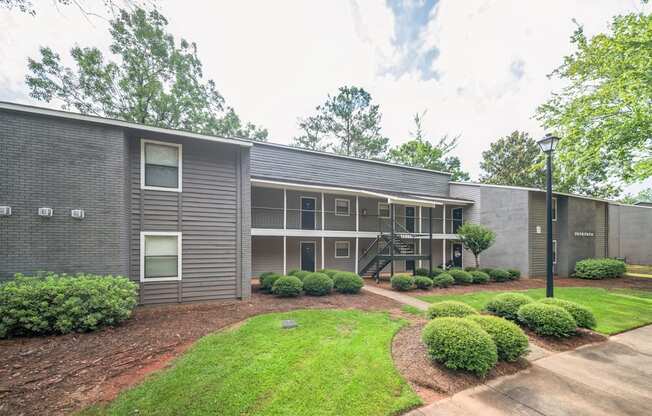 A grey building with a green lawn in front.