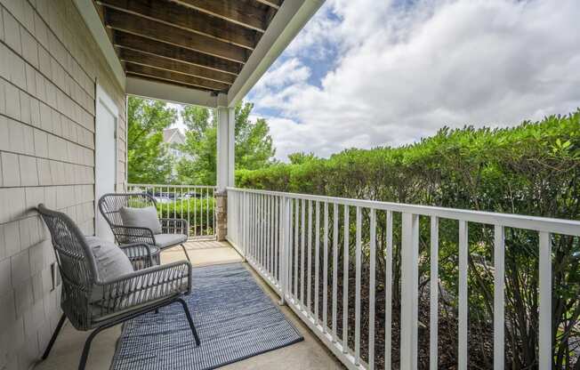 a balcony with two chairs and a view of the water