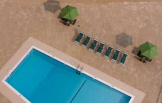 an aerial view of a swimming pool with green umbrellas and chairs at Hampton Plaza Apartments in Towson, MD 21286