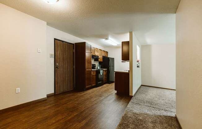 Grand Forks, ND Grandview II Apartments. A kitchen with black appliances and wood floors with a dining room and living slightly in shot.