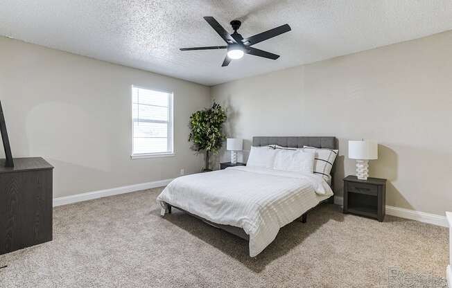 an empty bedroom with a bed and a ceiling fan