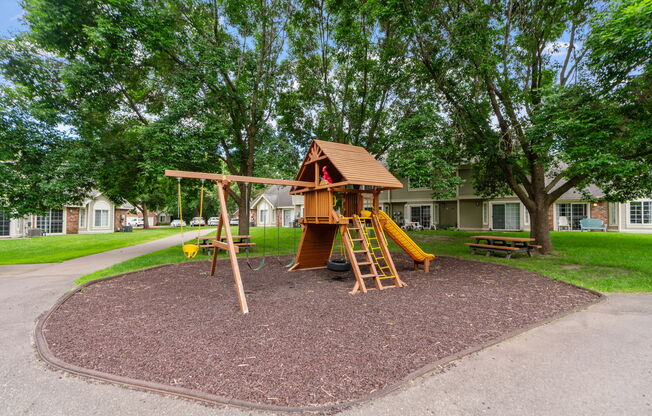 A playground with a wooden swing set and a yellow slide.