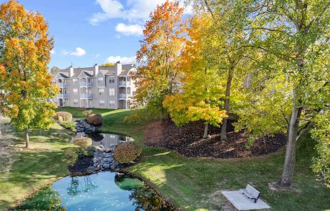 a park with a pond and trees in front of a building