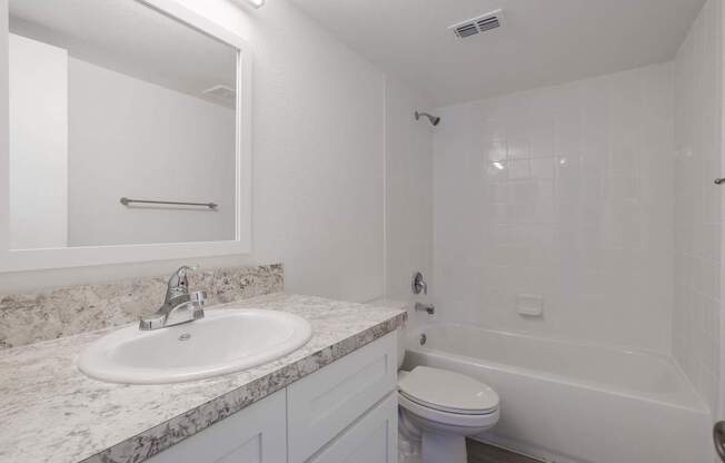 A white bathroom with a sink, toilet, and bathtub.