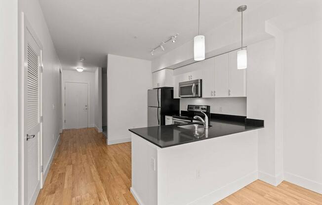 A kitchen with a black countertop and white cabinets.